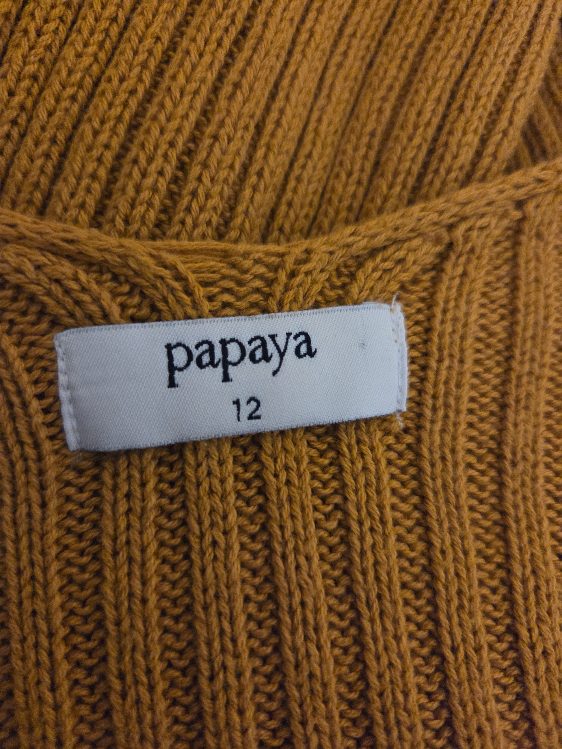 Close-up of a mustard yellow fabric with a 'papaya' label on a textured background