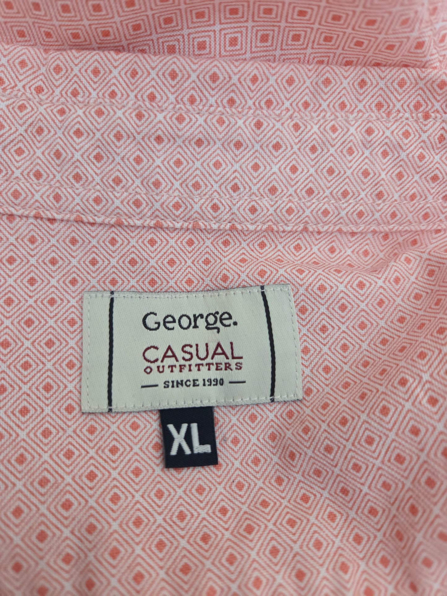 Close-up of a shirt label with 'George Casual Outfitters' on a patterned shirt.