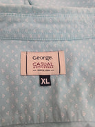 Close-up of a shirt label on a light blue patterned shirt with 'George Casual Outfitters' branding.