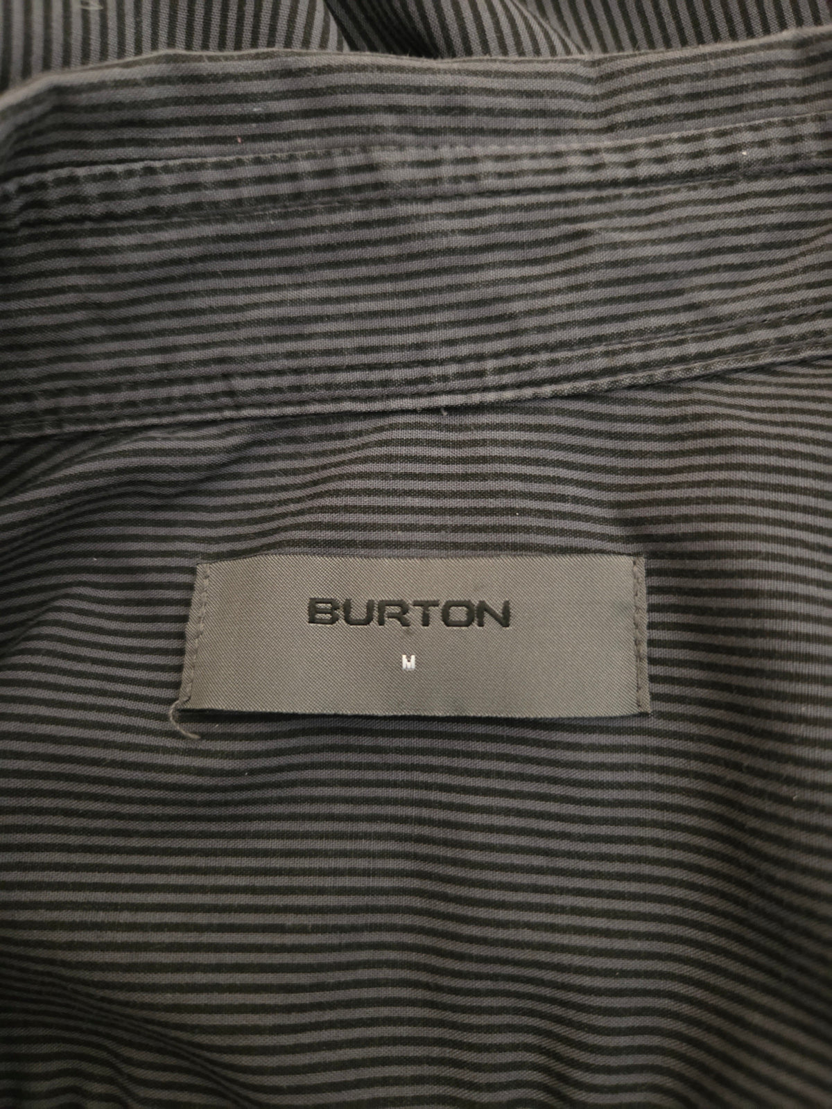 Close-up of a striped shirt with a Burton label on a dark background