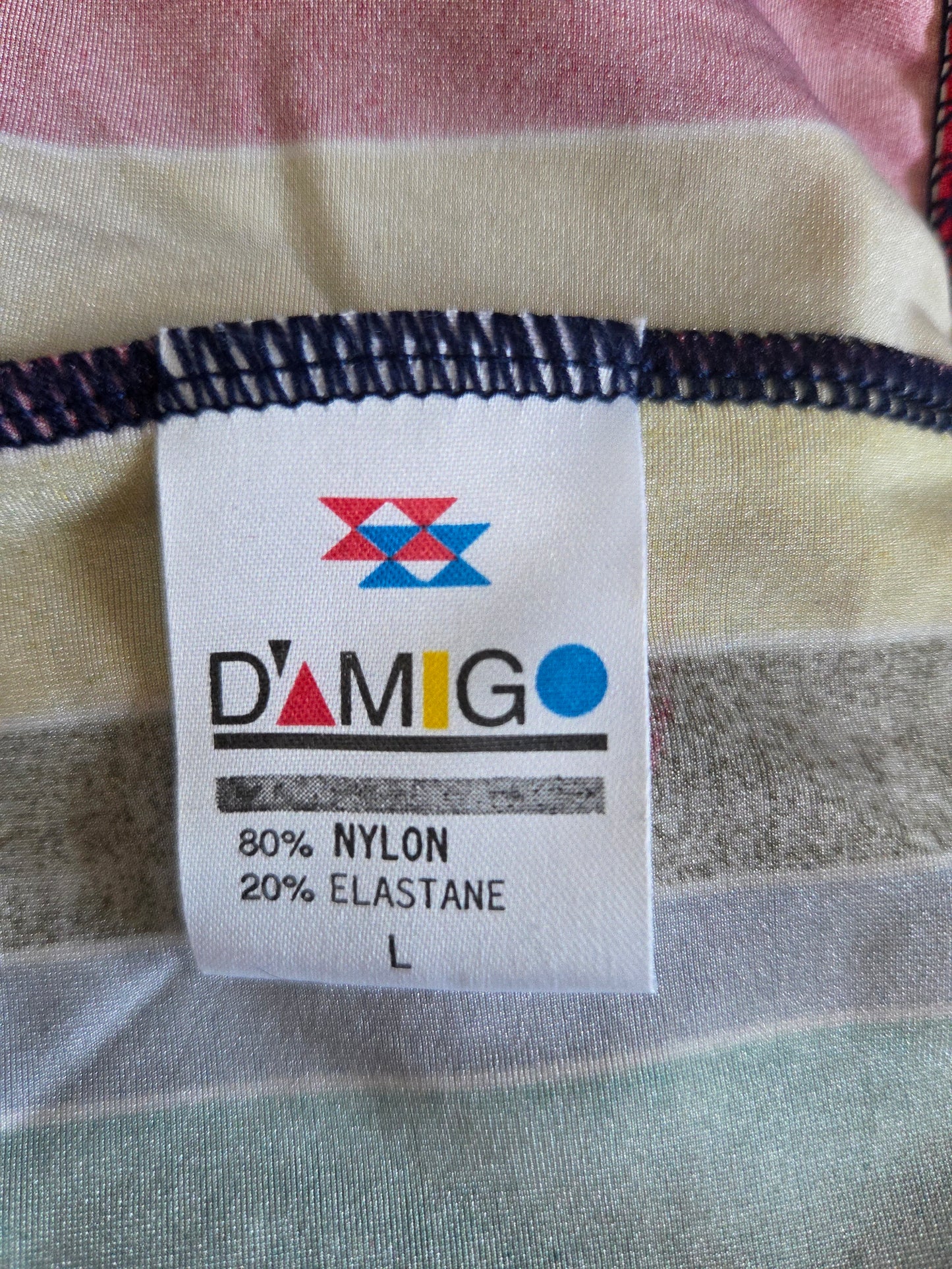 Fabric label with 'Damigo' brand name and material information on a striped fabric background.