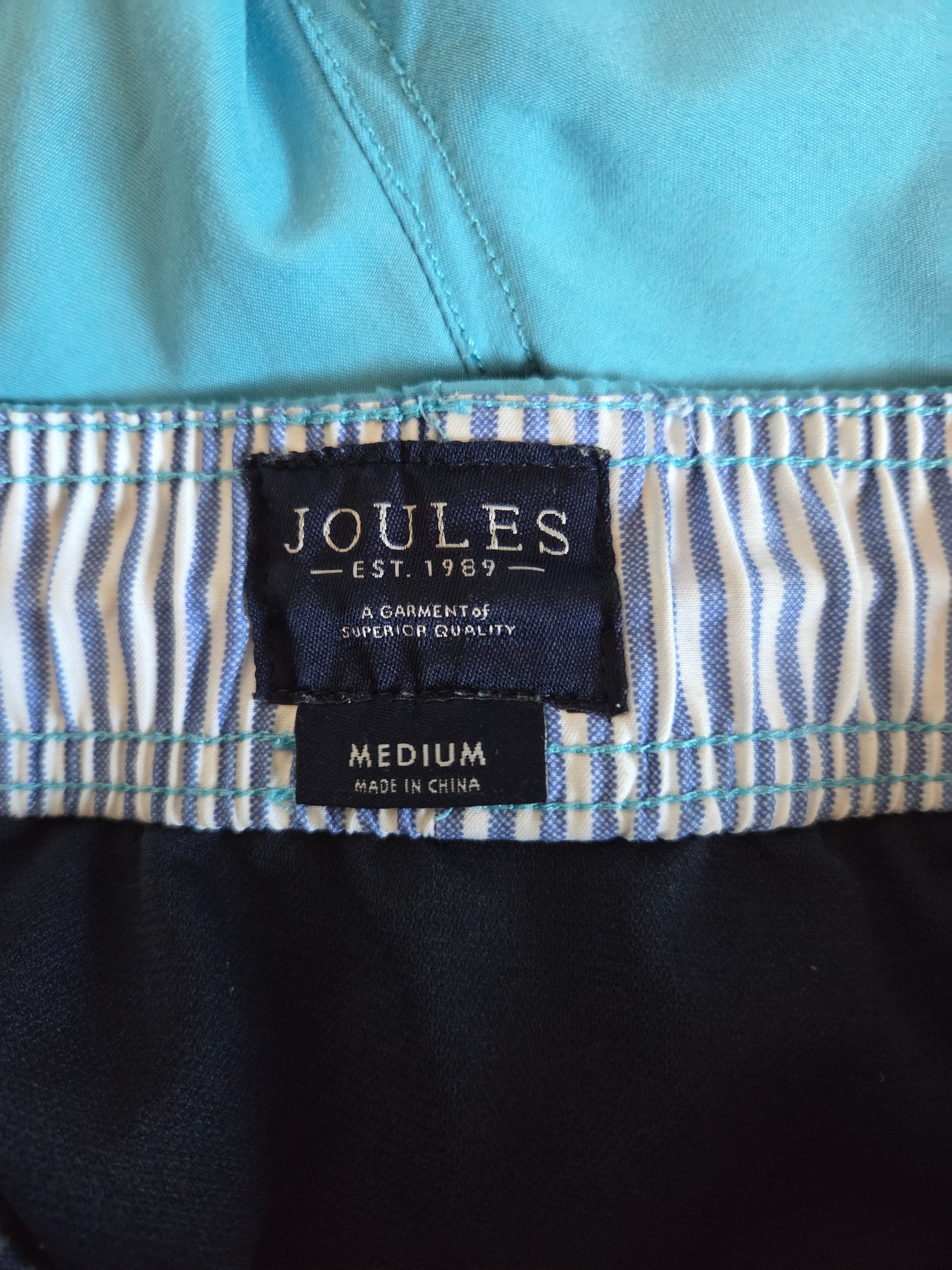 Close-up of a Joules label on a garment with a blue and white striped pattern.