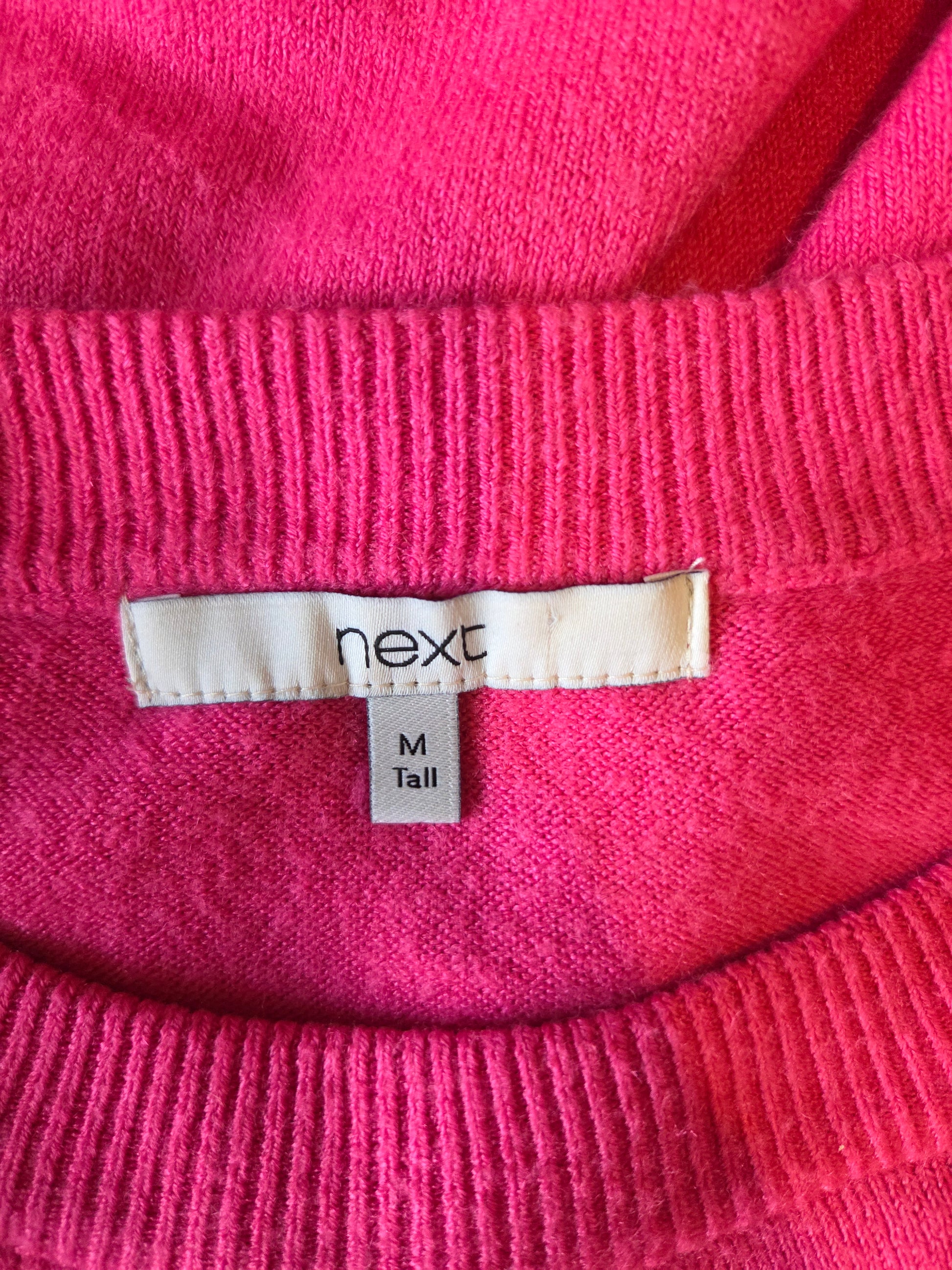 Close-up of a pink fabric with a Next size label