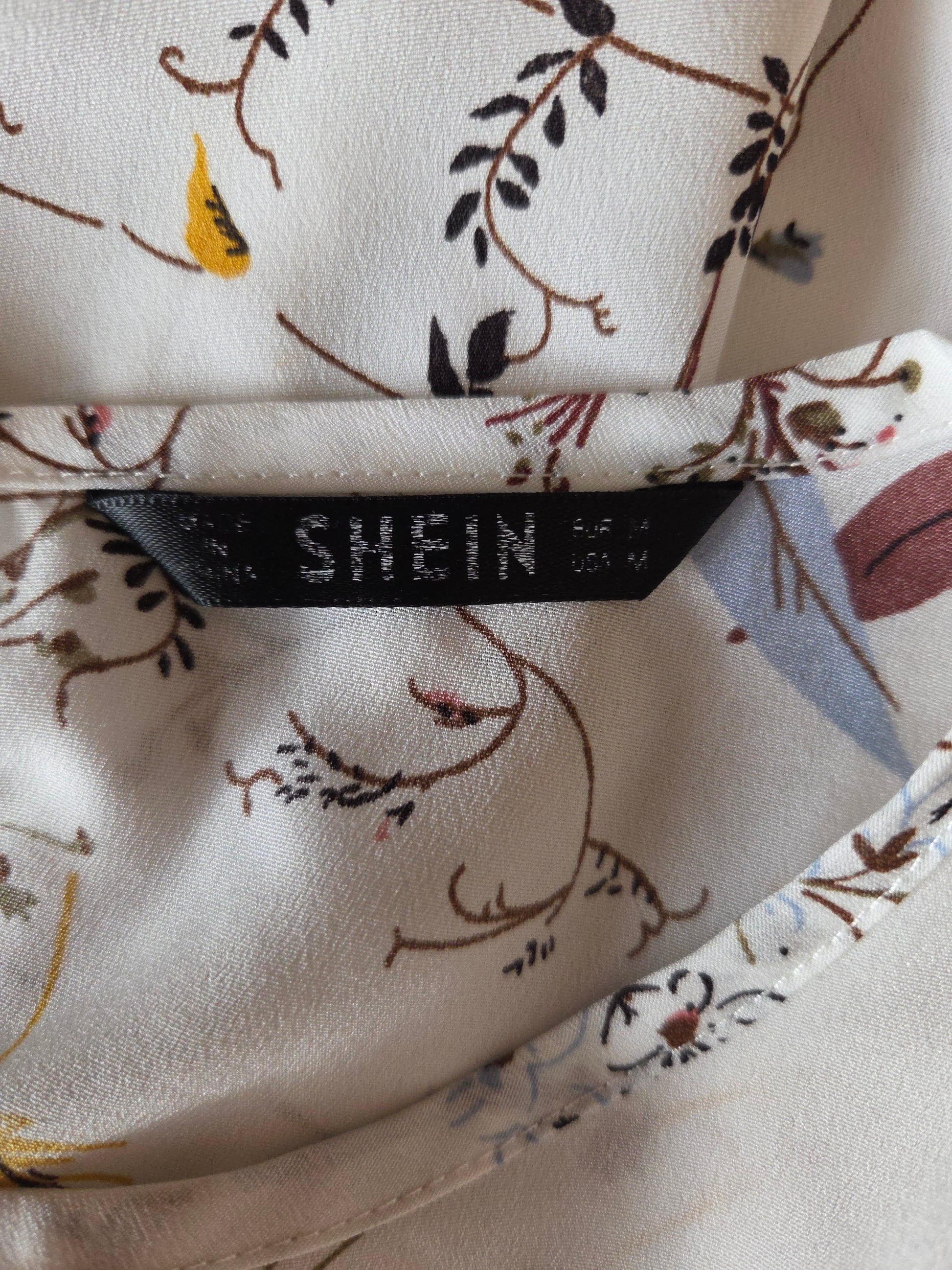 Close-up of a fabric with floral patterns and a black label on a beige background