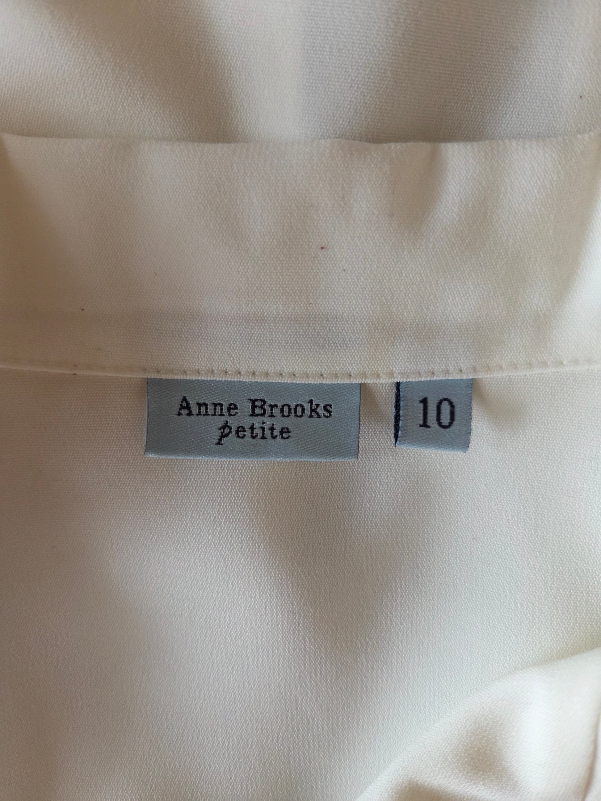 Close-up of a  'Anne Brooks petite' label on a white background