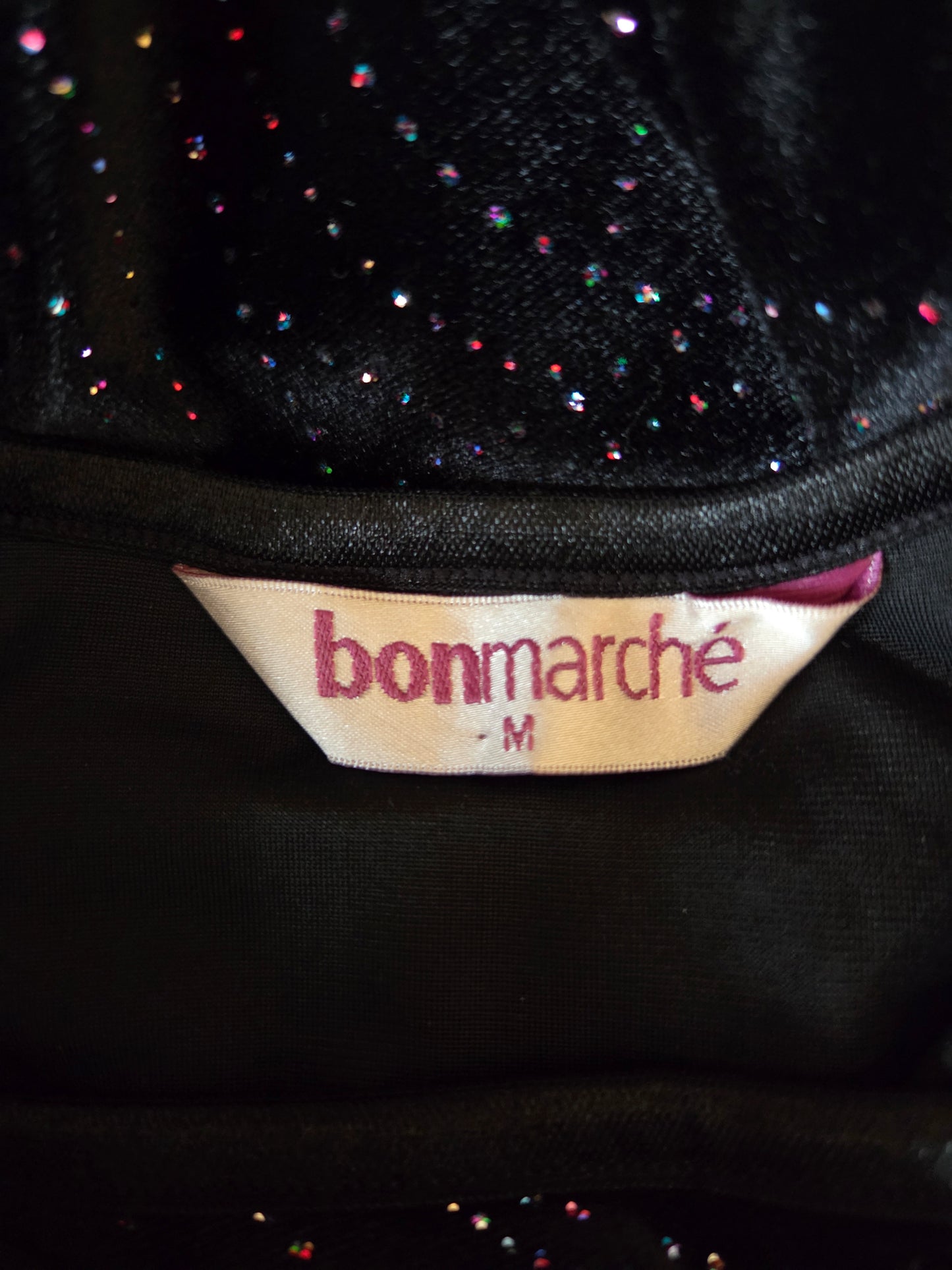 Close-up of a 'bonmarché' label on a black textured fabric background