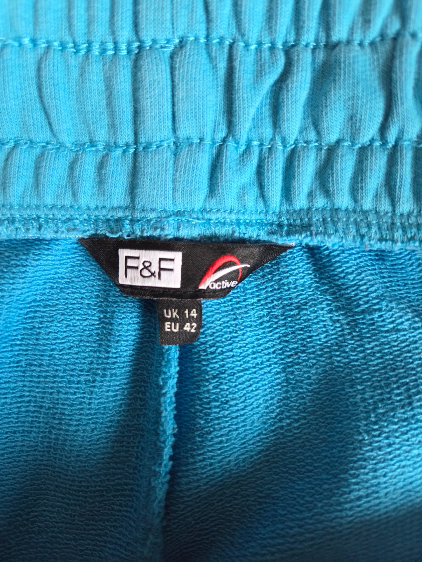 Close-up of a blue fabric with a size label featuring 'F&F' branding.