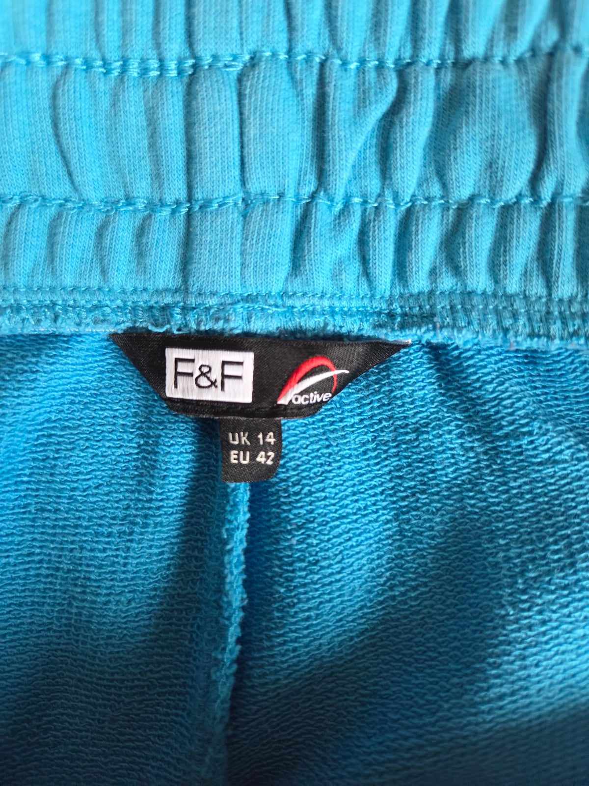 Close-up of a blue fabric with a size label featuring 'F&F' branding.