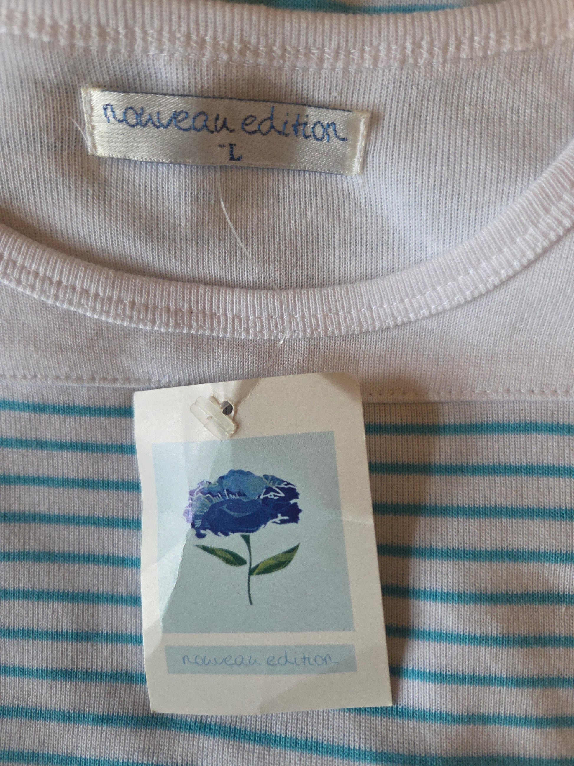 Close-up of a striped shirt with a tag featuring a blue flower illustration and text.
