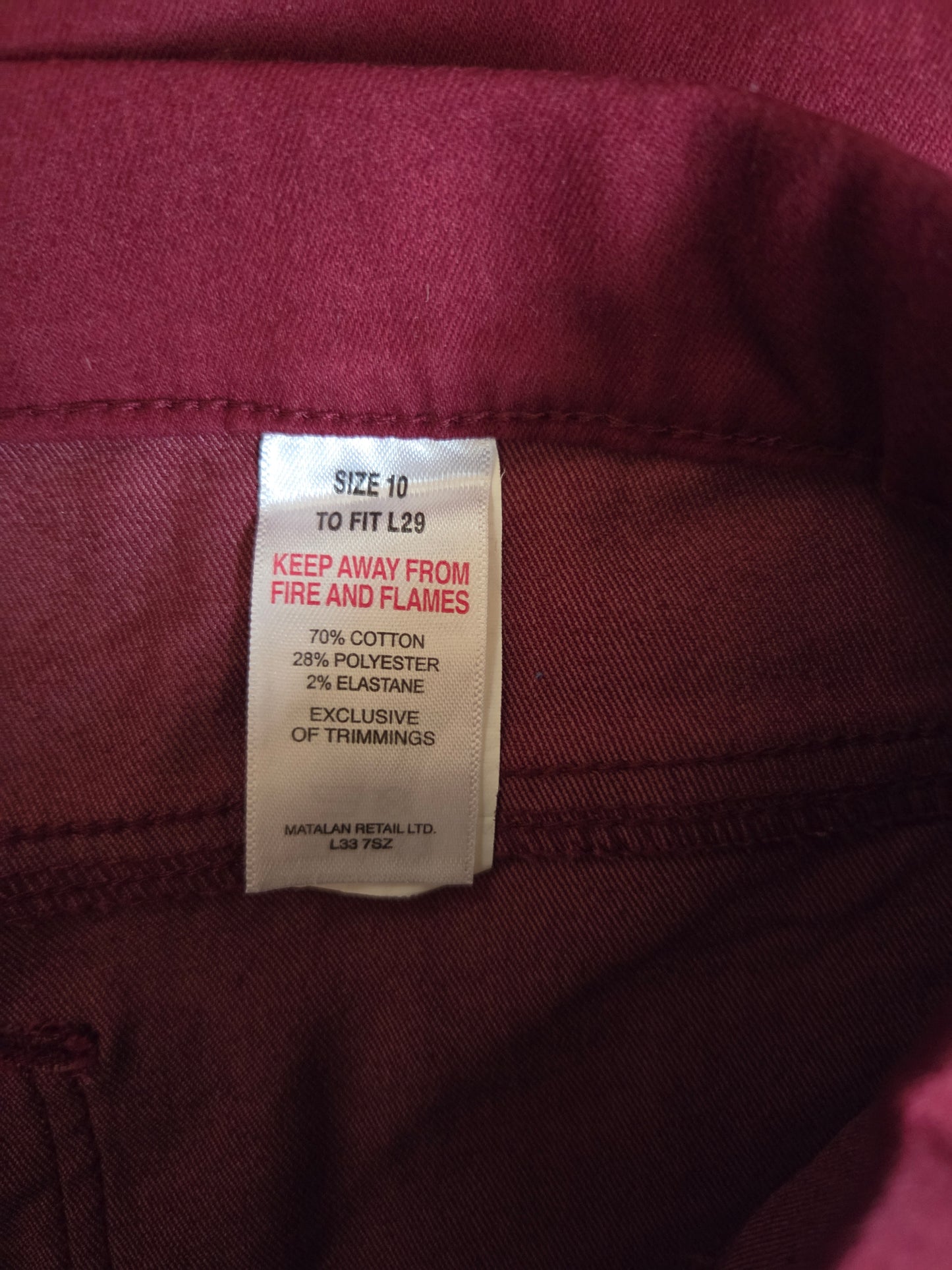 Close-up of a clothing tag on a maroon fabric background