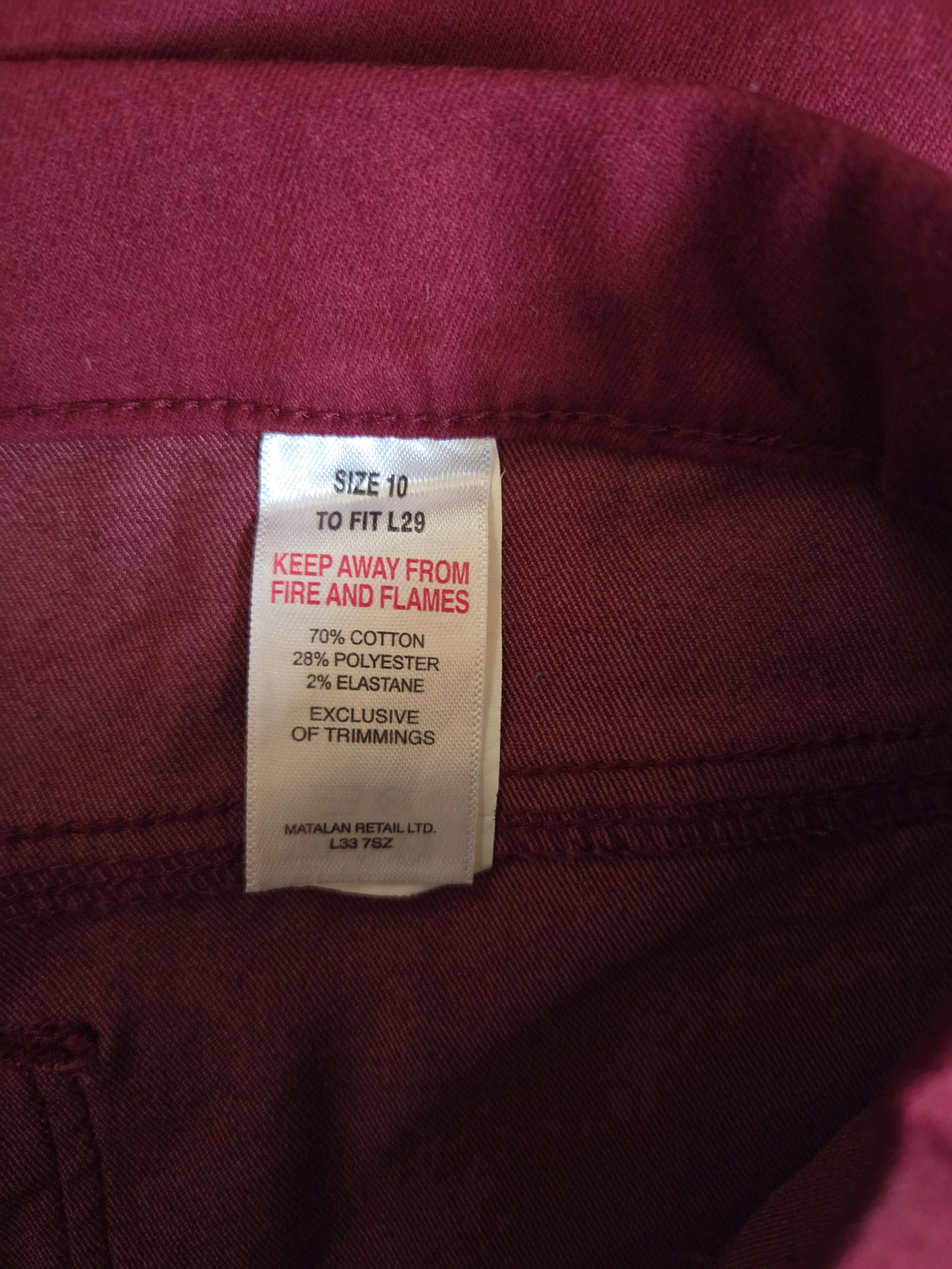 Close-up of a clothing tag on a maroon fabric background