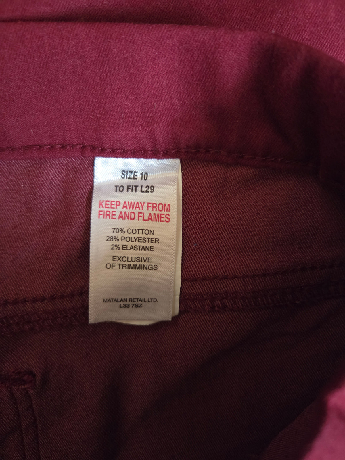 Close-up of a clothing tag on a maroon fabric background