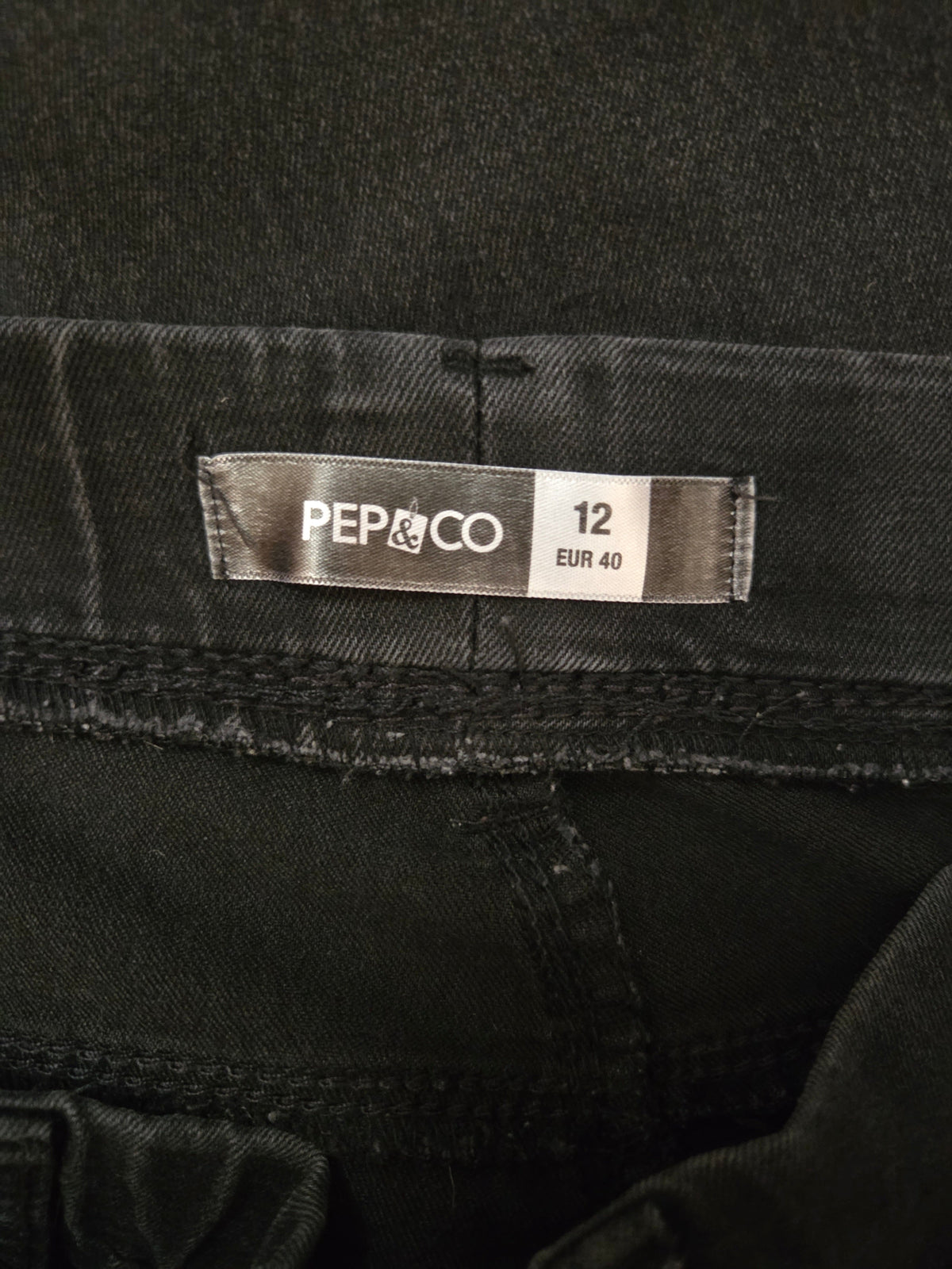 Black denim fabric with a 'Pep & Co' label showing size 12.