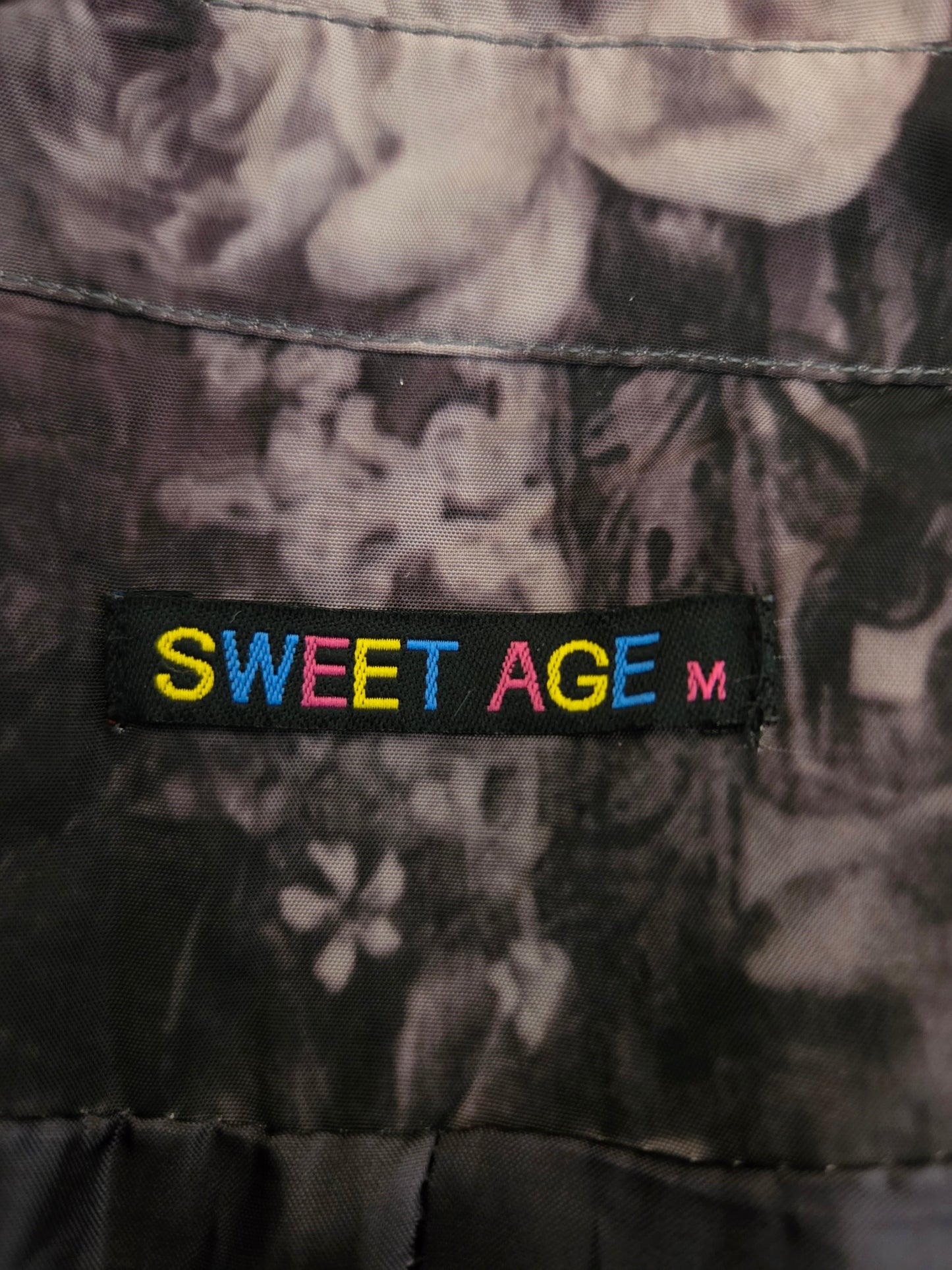 Floral patterned fabric with a 'Sweet Age' label in multicolor on a black background