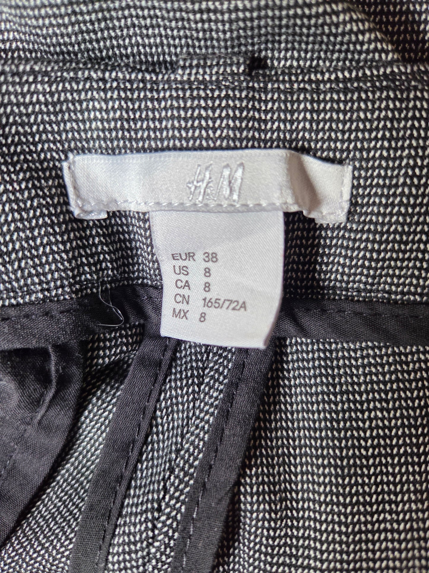 Close-up of a fabric tag on a textured black and white garment.