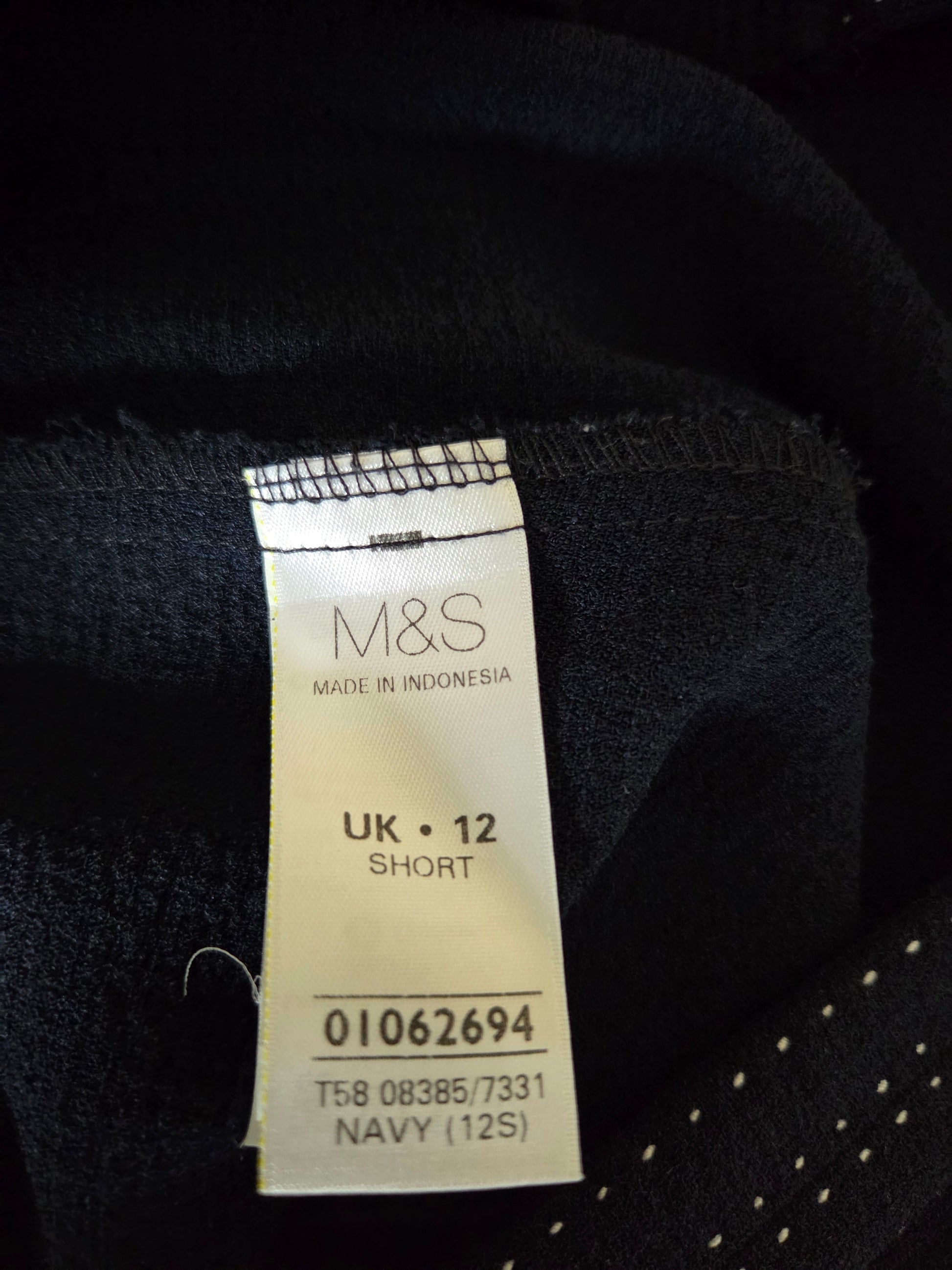 Clothing tag with M&S branding on a dark fabric background