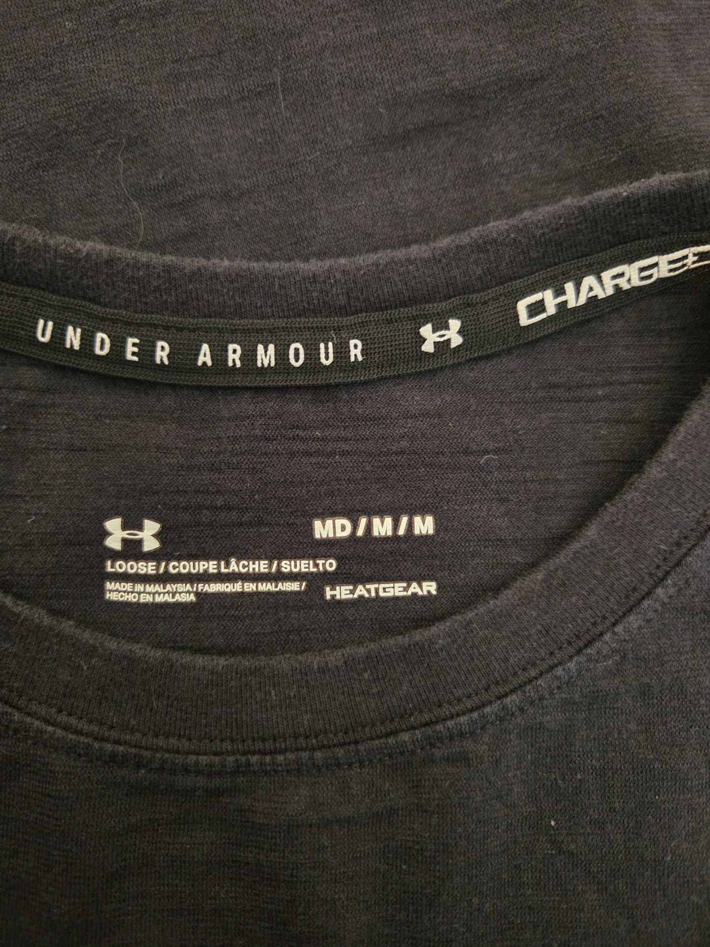 Close-up of a black Under Armour shirt with branding and size label.