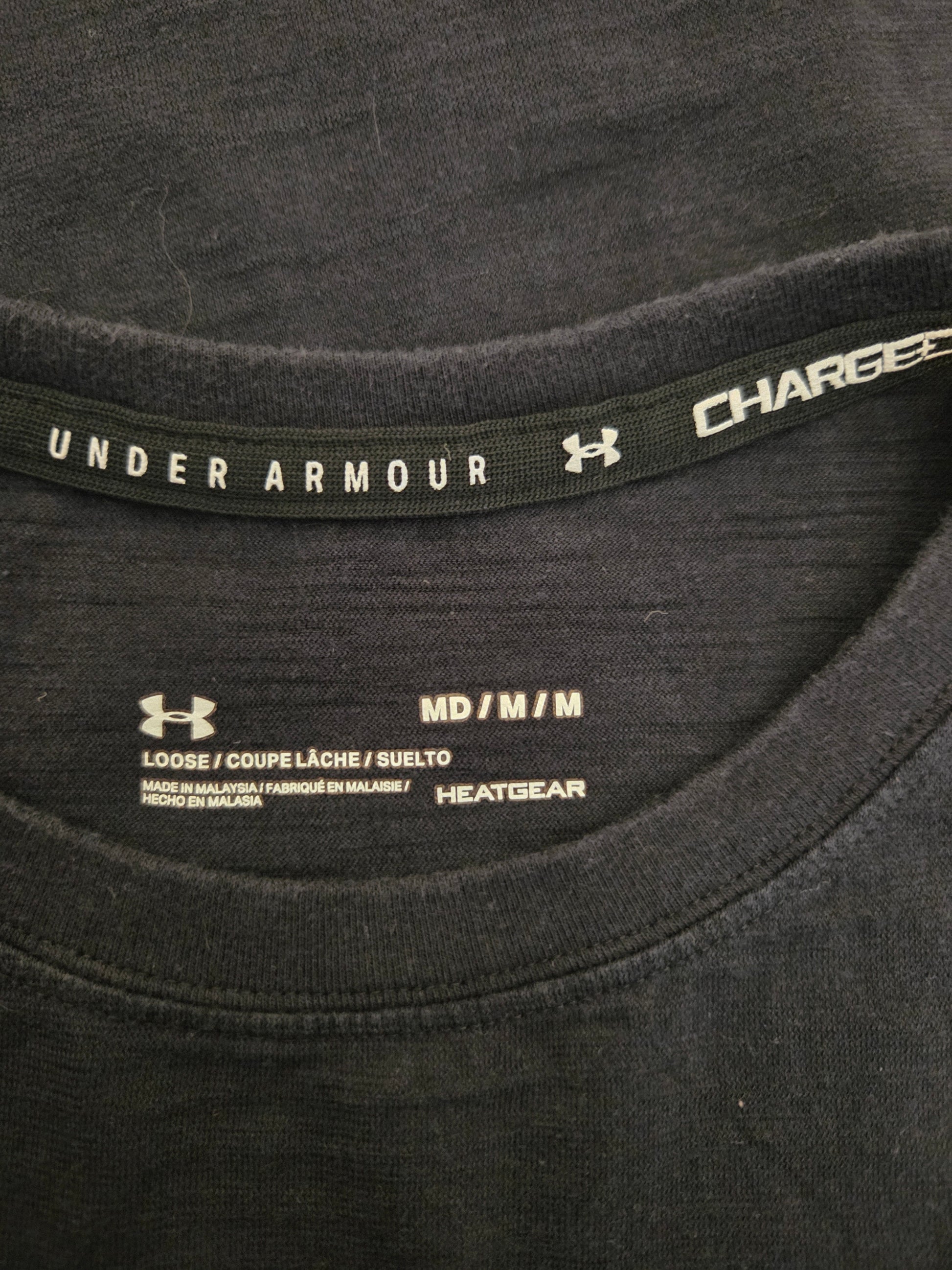Close-up of a black Under Armour shirt with branding and size label.