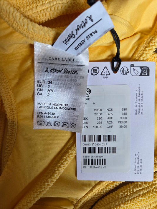 Care label and tag on a yellow garment with brand name visible