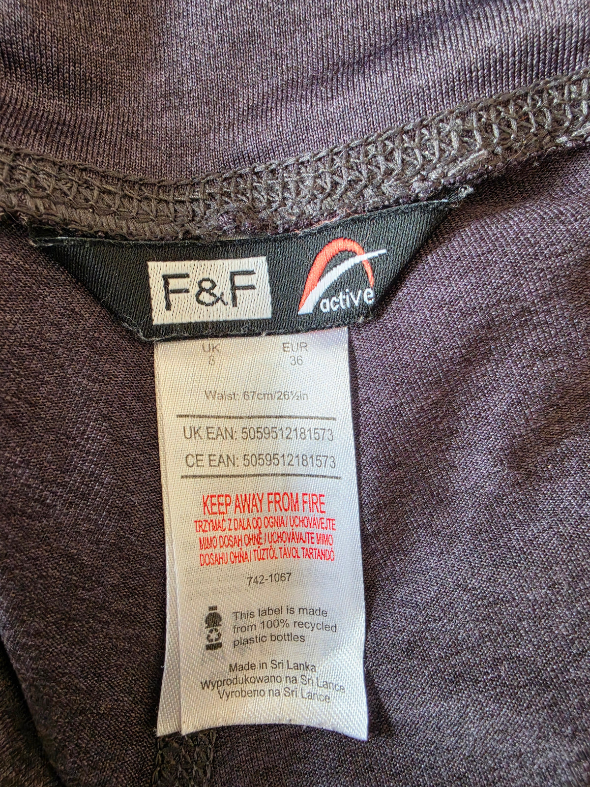 Close-up of a size label showing the F&F brand and 'active' line, with a white size and care instruction tag below on dark heathered fabric.