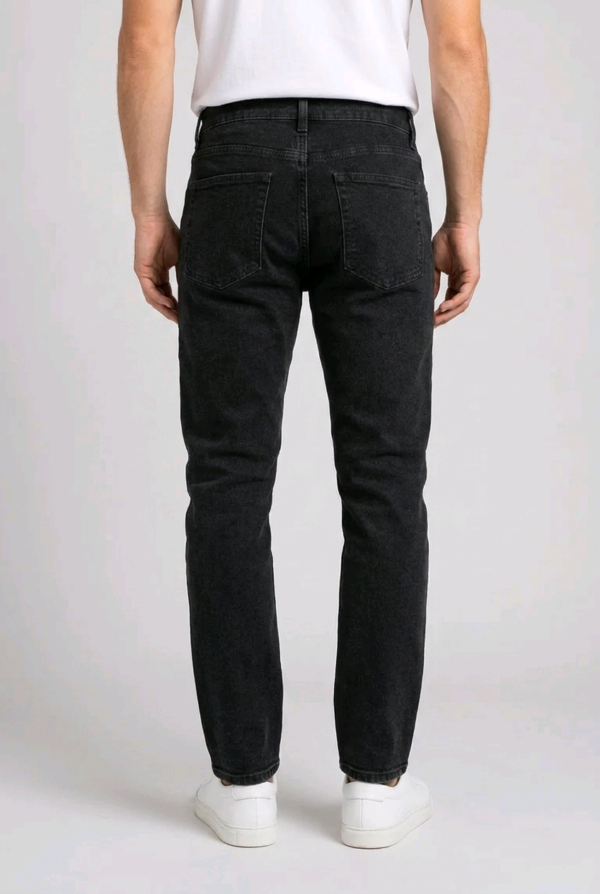 Person wearing black jeans and white shoes on a plain background