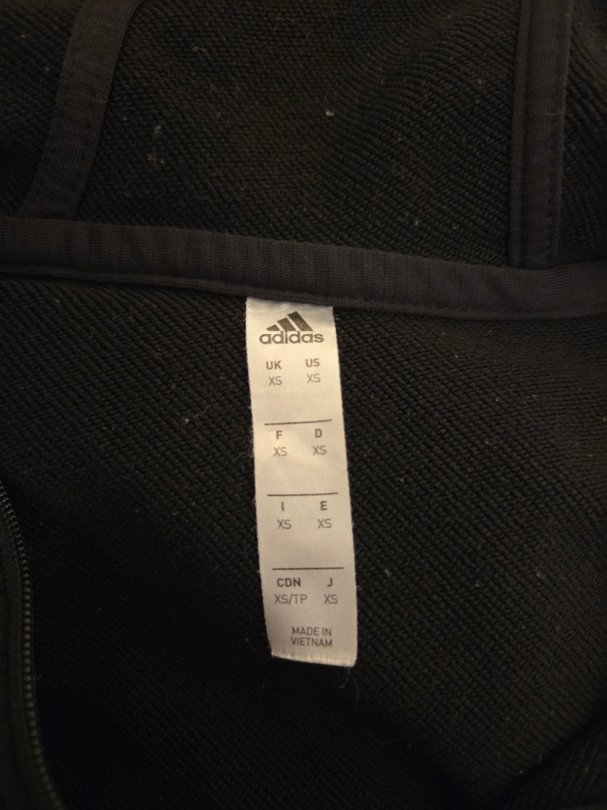 Black Adidas garment with a label on a black background