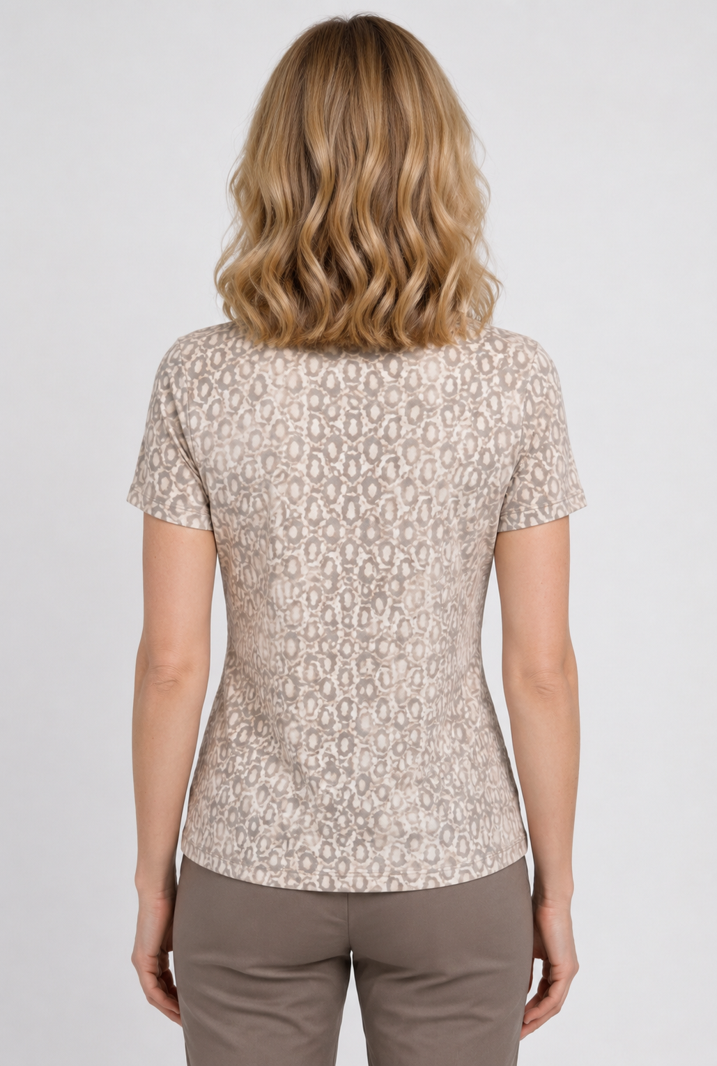 A woman viewed from the back wearing a short-sleeve beige top 