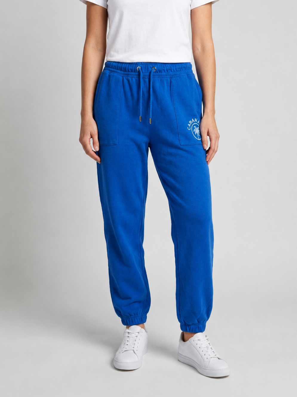 Woman wearing blue joggers with a logo and a white t shirt