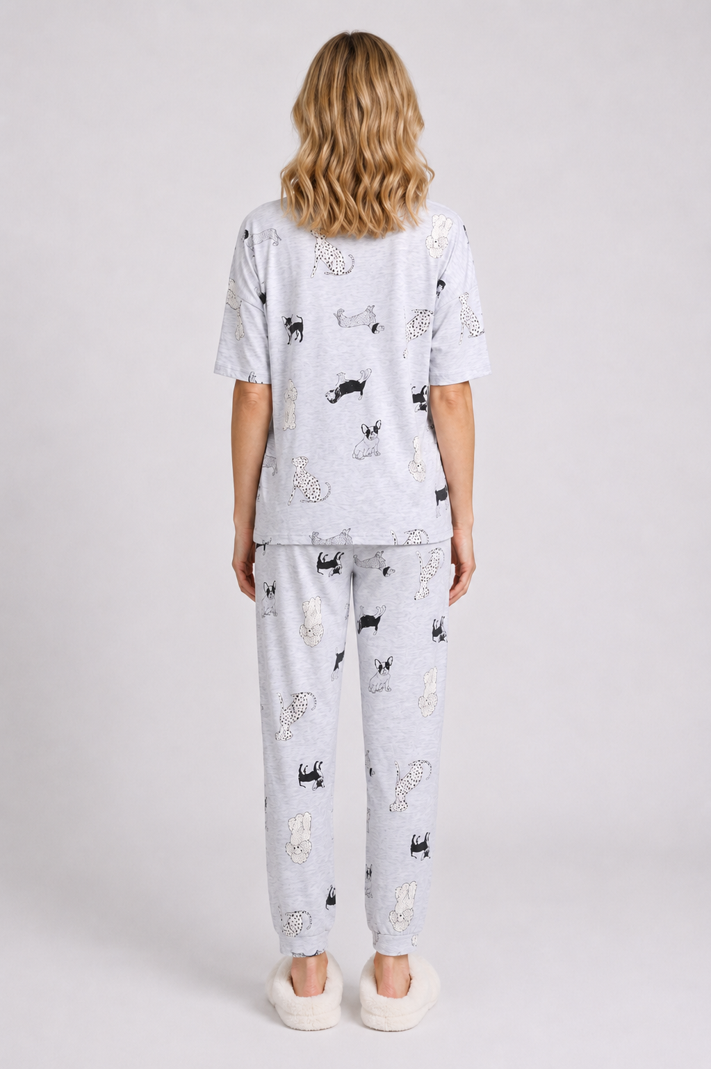 Woman wearing a light grey pajama set with black dog prints on 