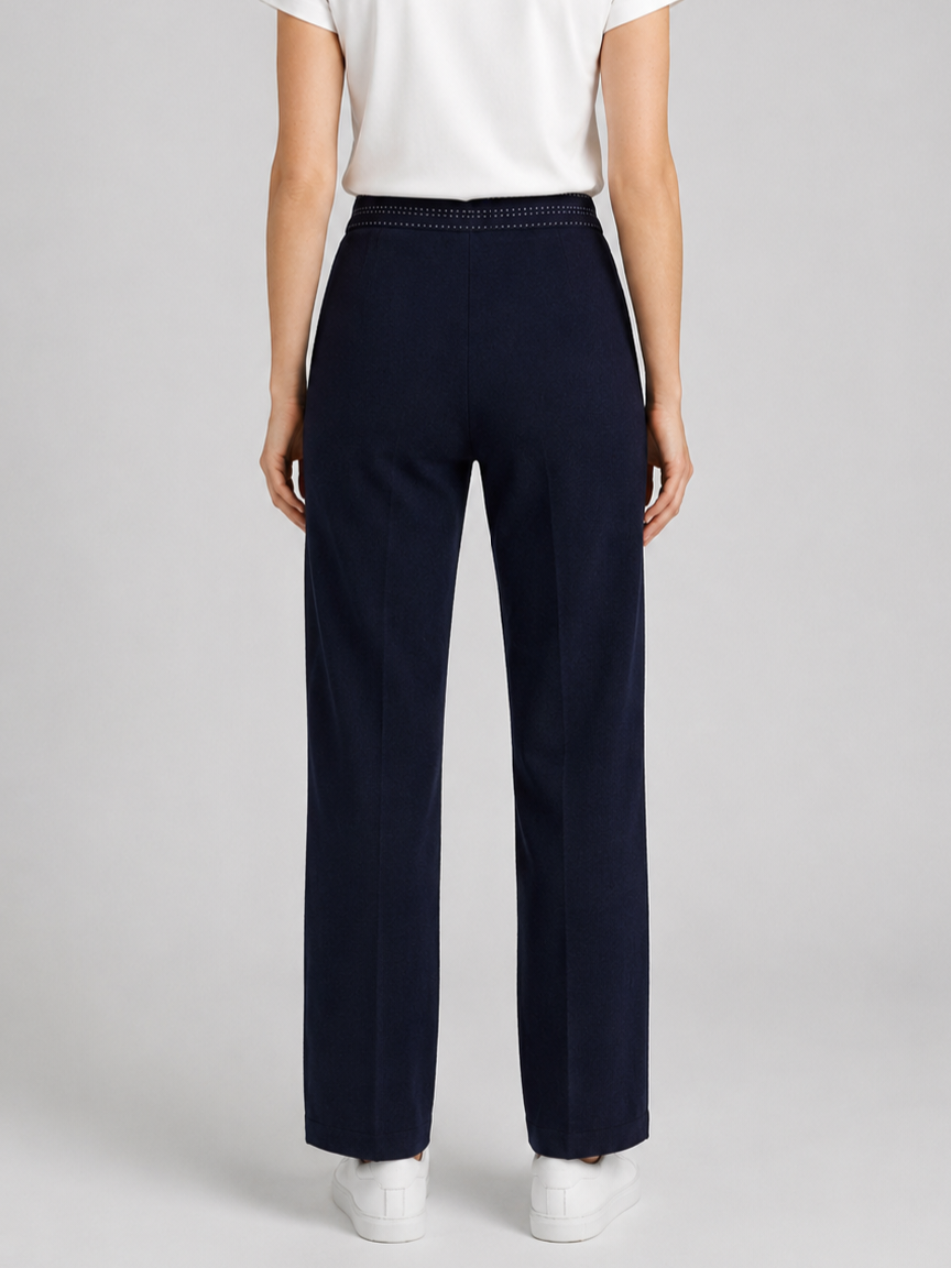 Woman wearing navy trousers and a white top 