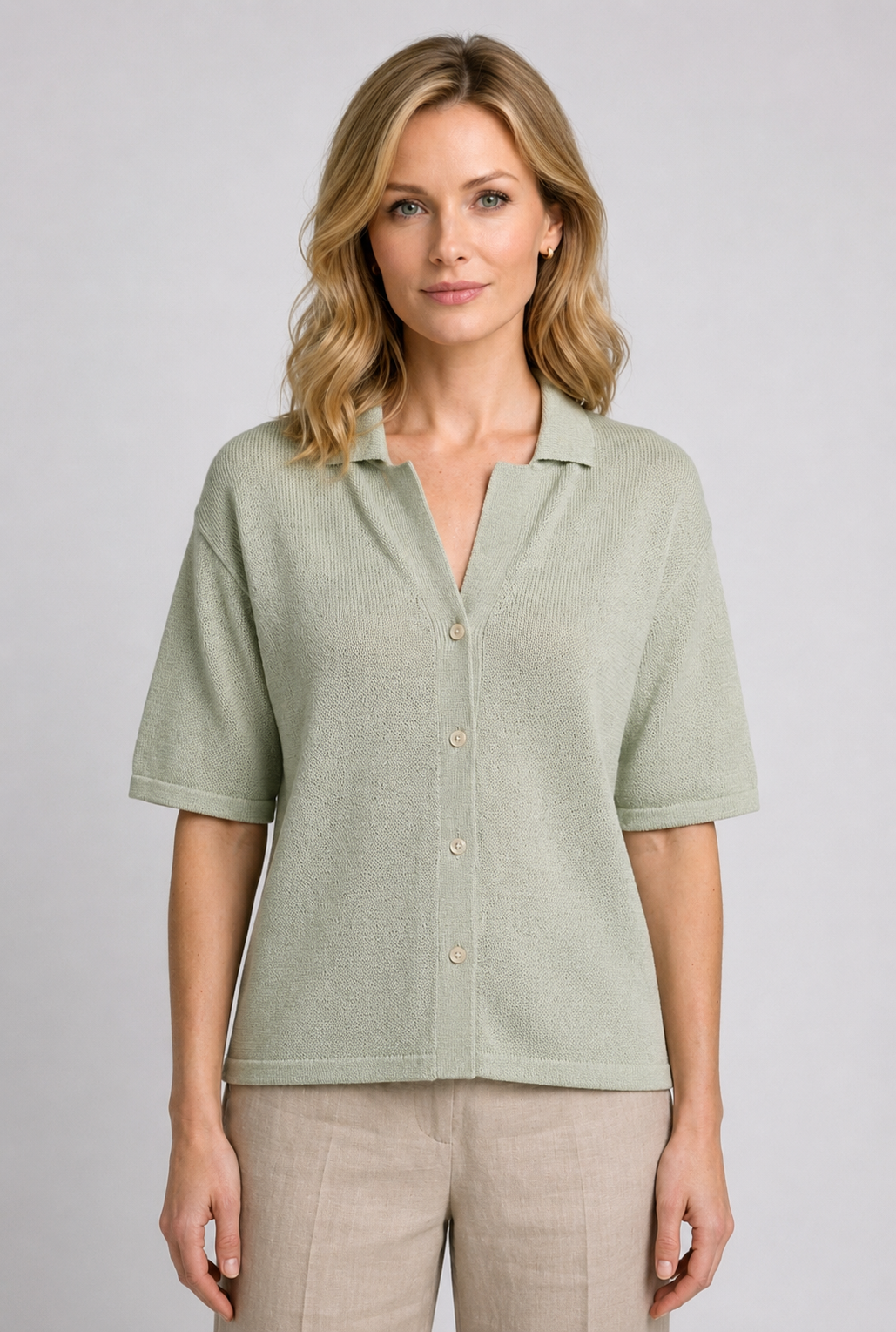 Woman wearing a light green button-up knit top and beige trousers