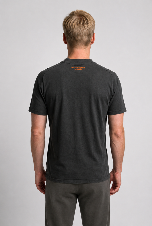 Man wearing a black t-shirt with a logo on the back against a gray background