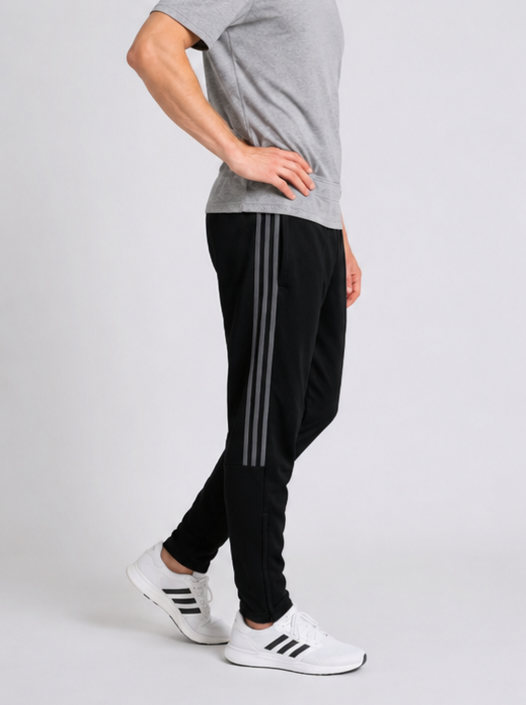 Man wearing black Adidas tracksuit bottoms with grey stripes