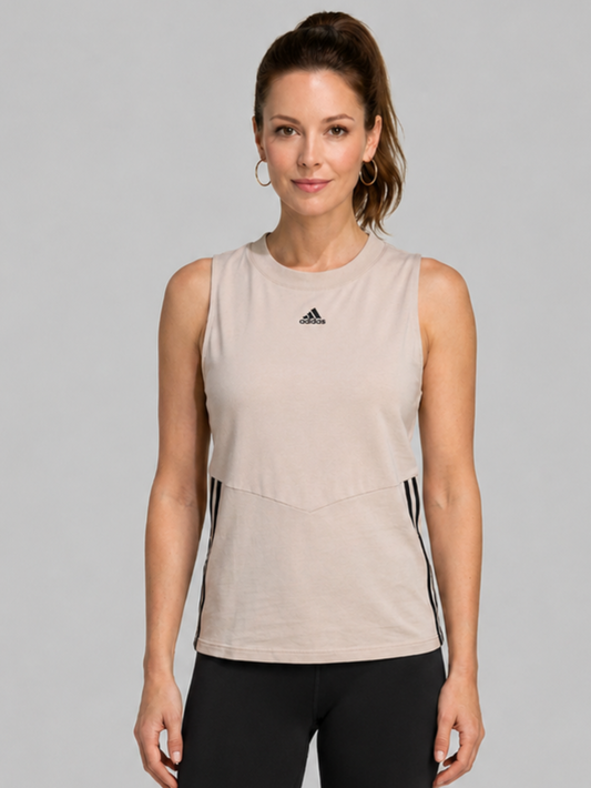 Woman wearing a beige sleeveless Adidas top with black leggings 
