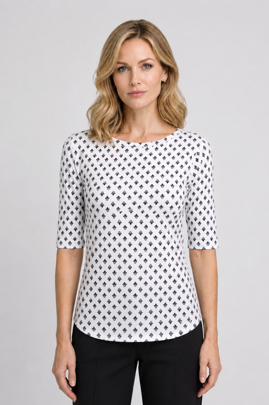 Woman wearing a white top with black pattern and black trousers