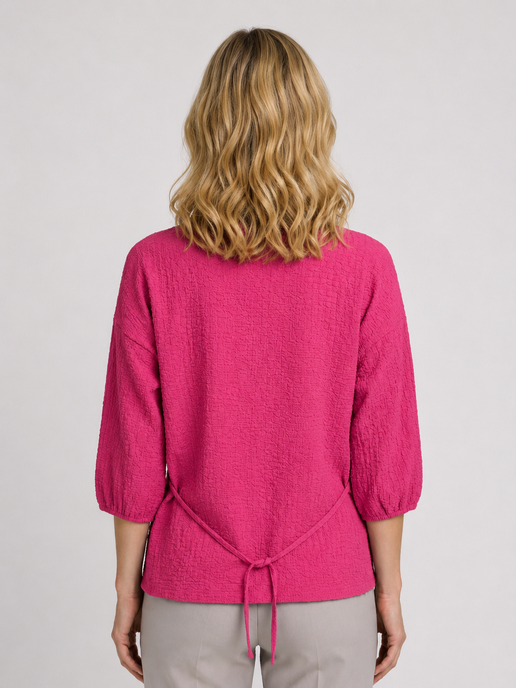 Woman wearing a pink blouse with a tie detail 