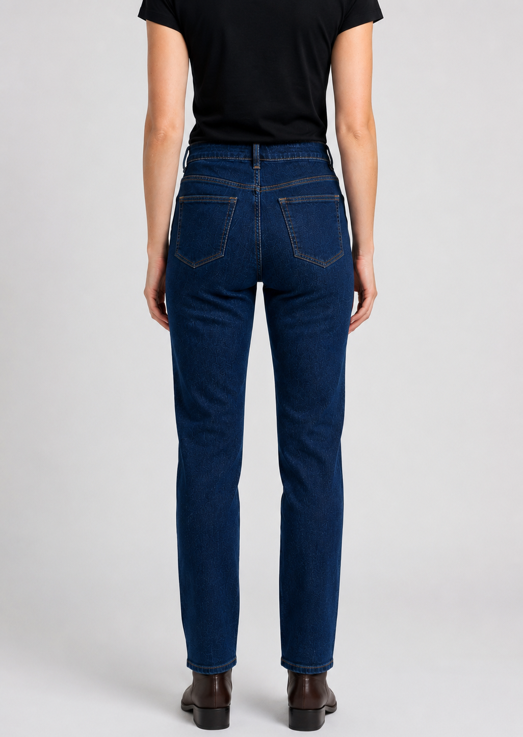 woman wearing blue jeans and a black shirt on a light gray background