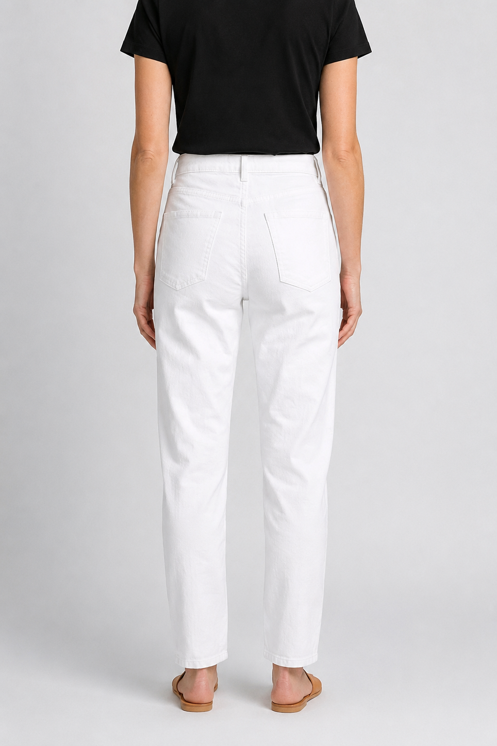 woman wearing a black top and white pants on a plain background