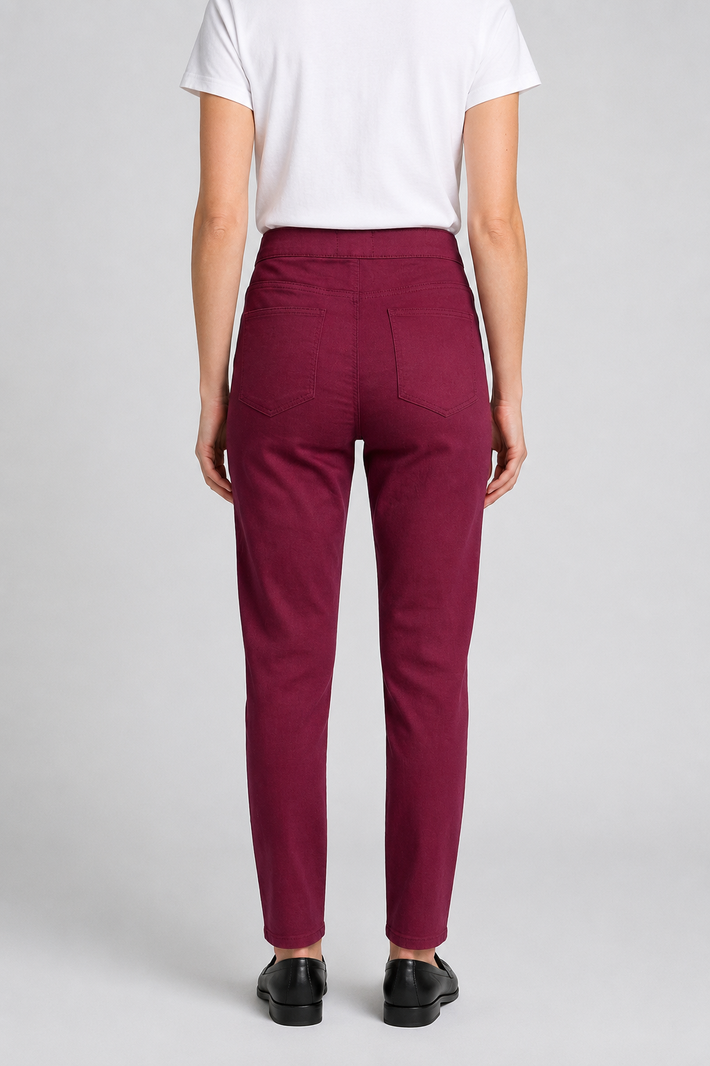 woman wearing maroon pants and a white shirt on a light gray background