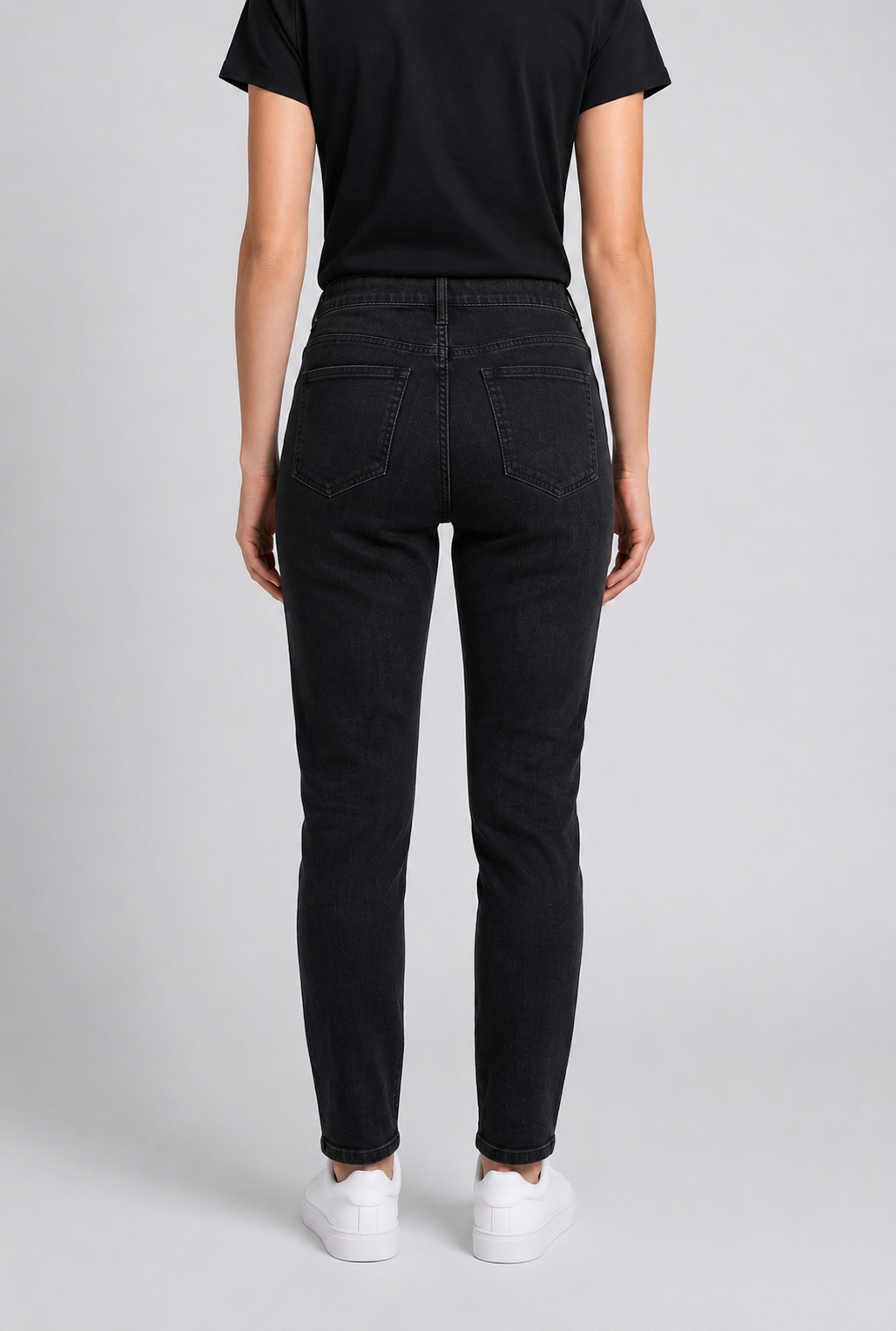 woman wearing black jeans and a black shirt on a light gray background