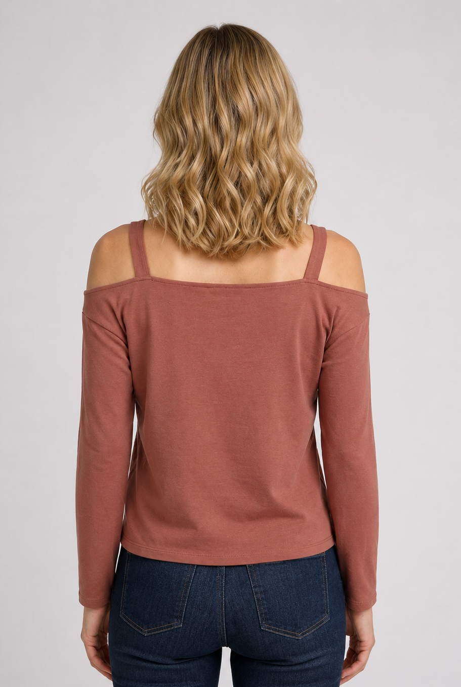 Woman wearing a dusty rose off-shoulder top and dark blue jeans