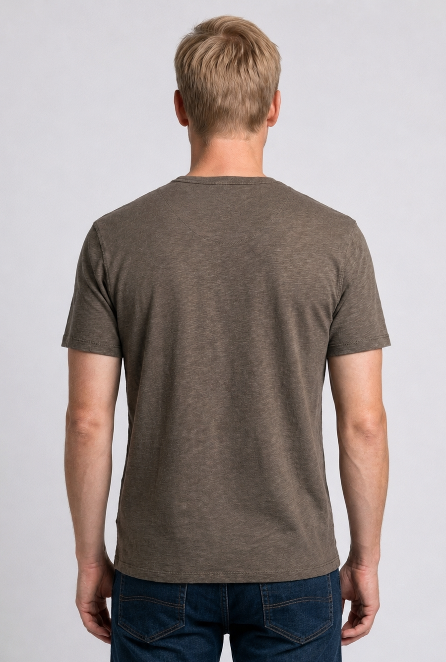Man wearing a Khaki t-shirt and blue jeans 
