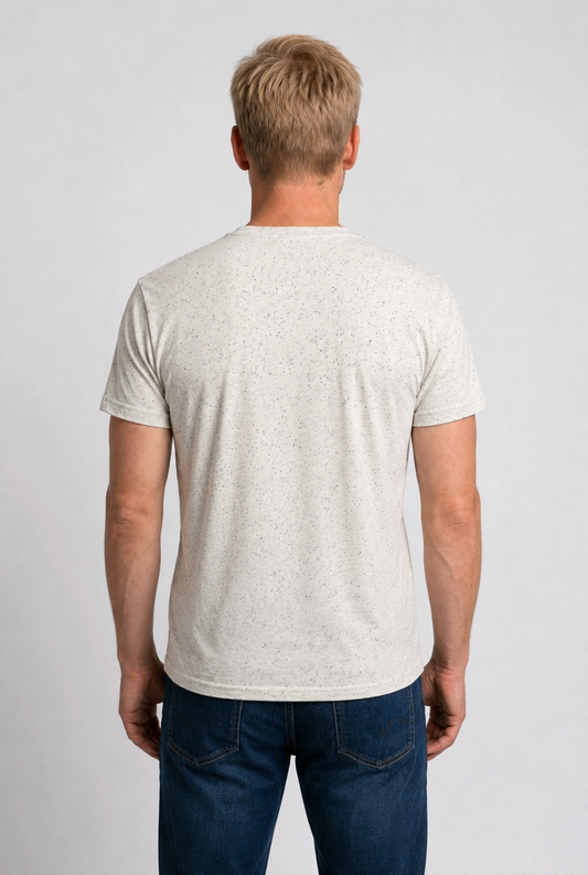 Man wearing a speckled white t-shirt and dark blue jeans 