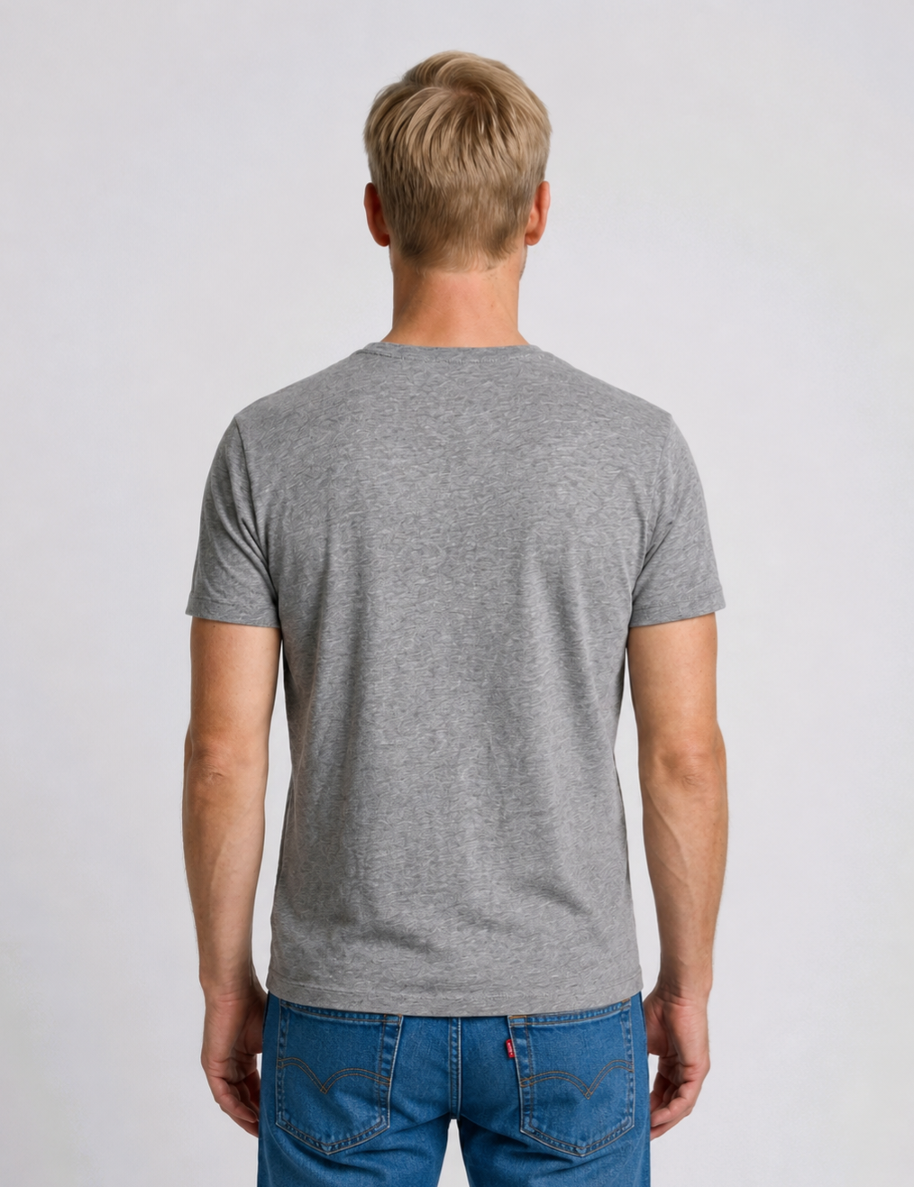 Man wearing a gray t-shirt and blue jeans 