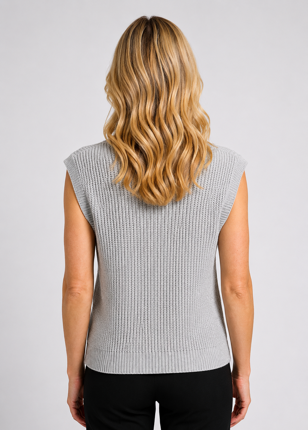 Person wearing a sleeveless grey knit top 