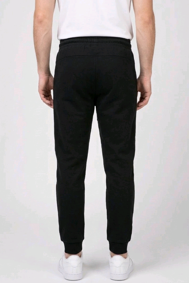 Person wearing black Reebok Delta joggers and white trainers