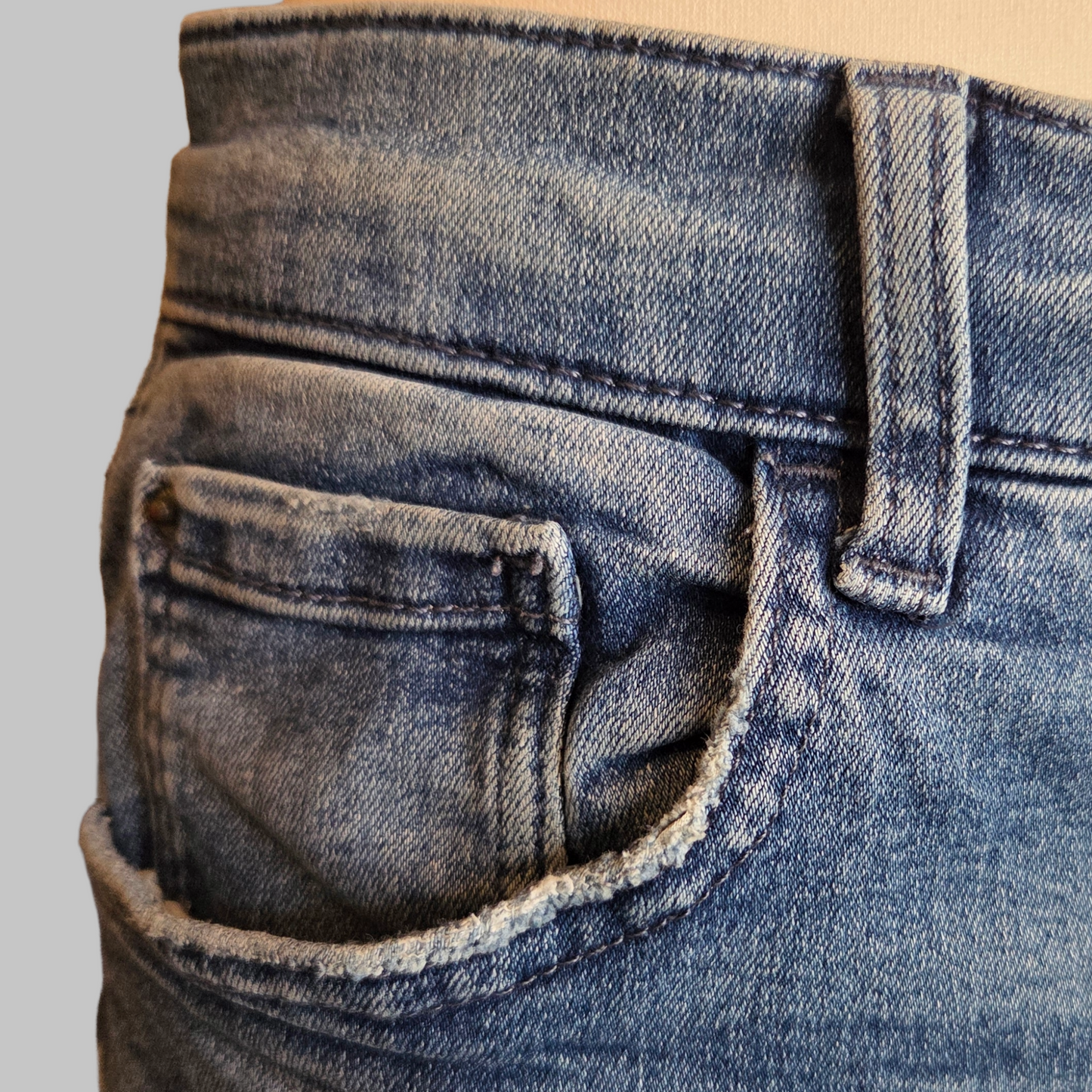 Close-up of blue jeans with a gray background