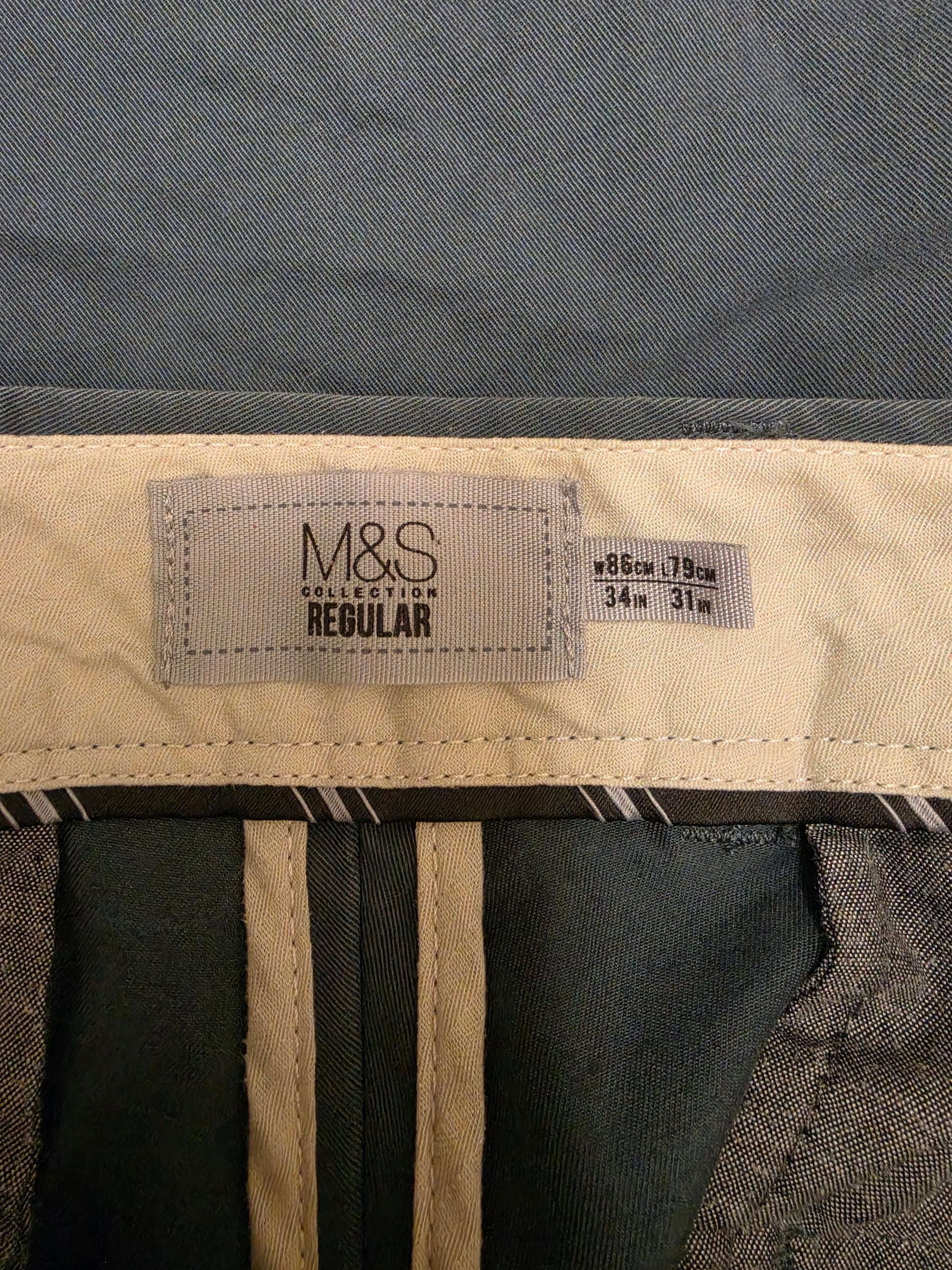 Close-up of the inner waistband of M&S Collection Regular trousers, showing the size label 'Regular 86cm / 79cm 34m 31m' and the brand tag.