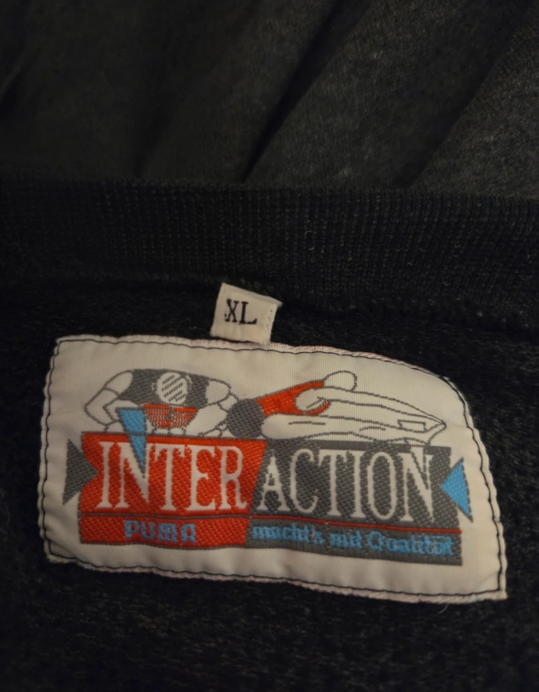 Close-up of a 'Puma Interaction' label on a dark fabric background