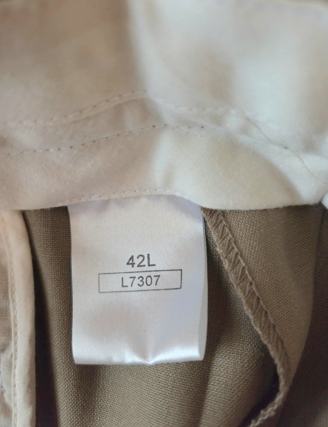 Close-up of beige trousers with a label showing size 42L